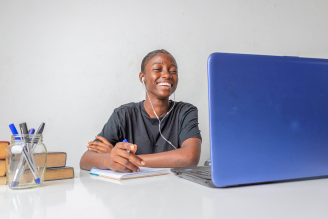 Jovem alegre estudando em frente ao computador
